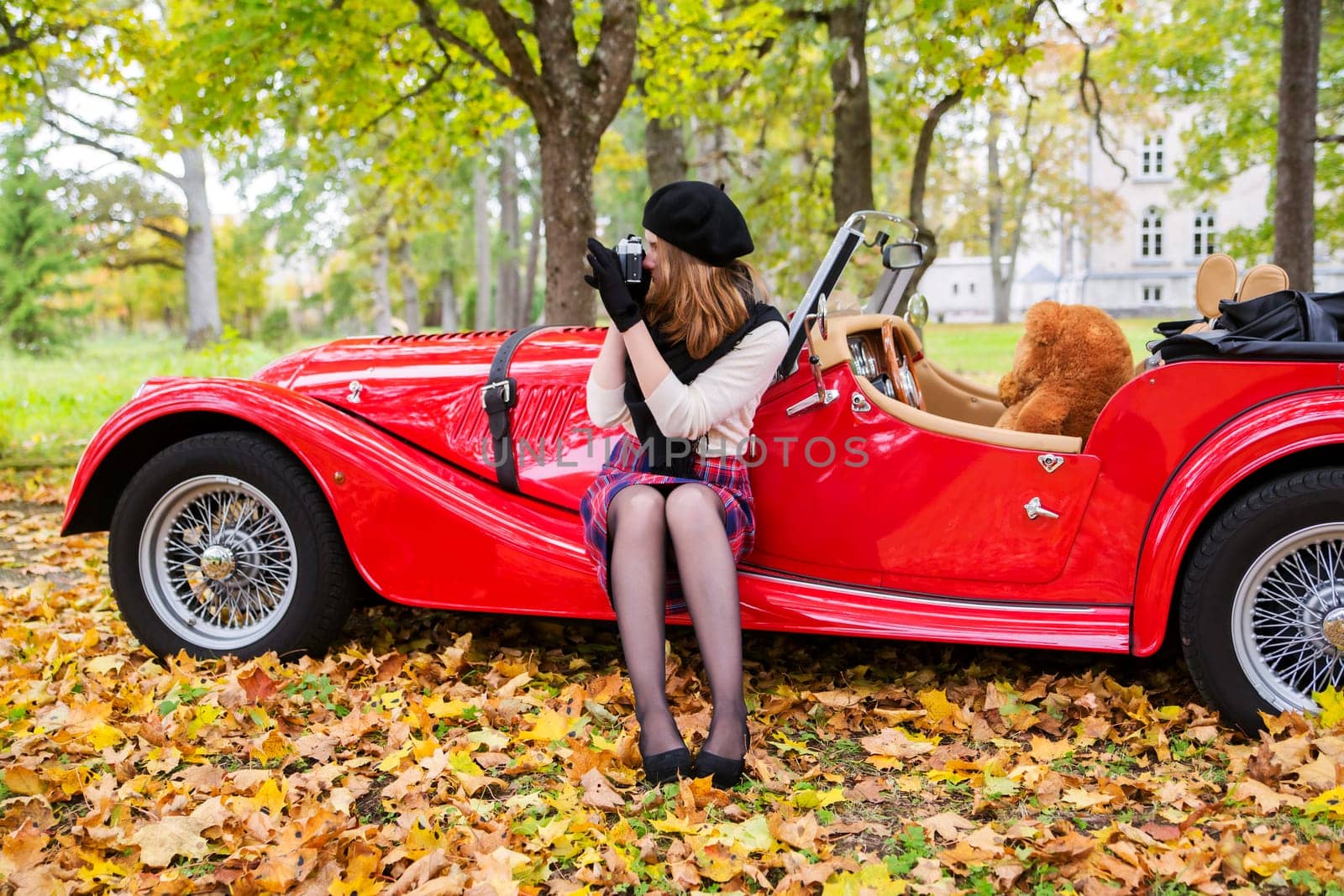 Woman take picture with red car on background