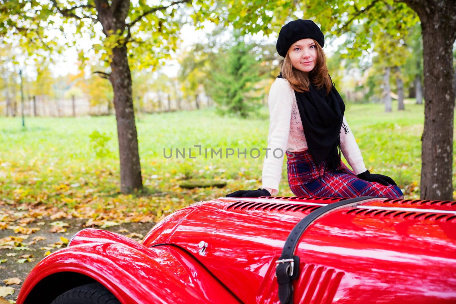 Young woman in skirt on red car cowling