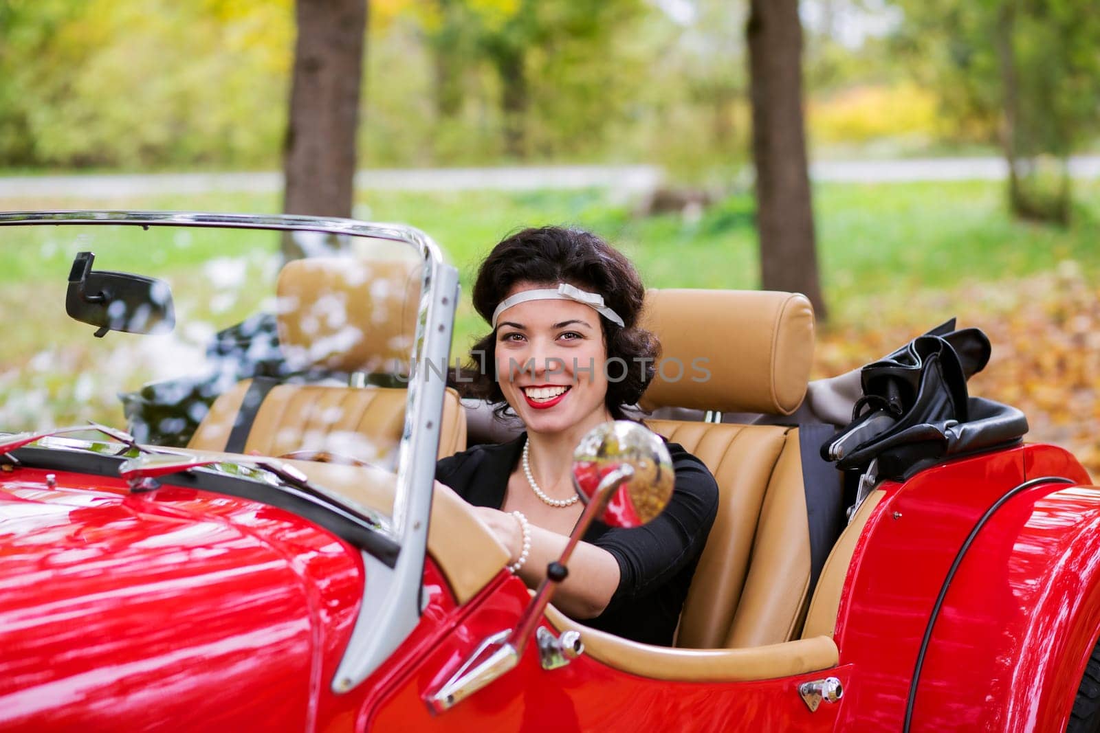 Smiling widely young woman after red car wheel