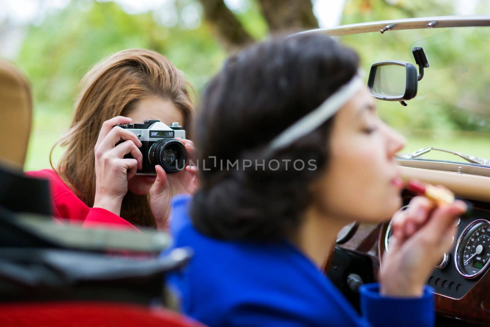One woman take photo of other at car