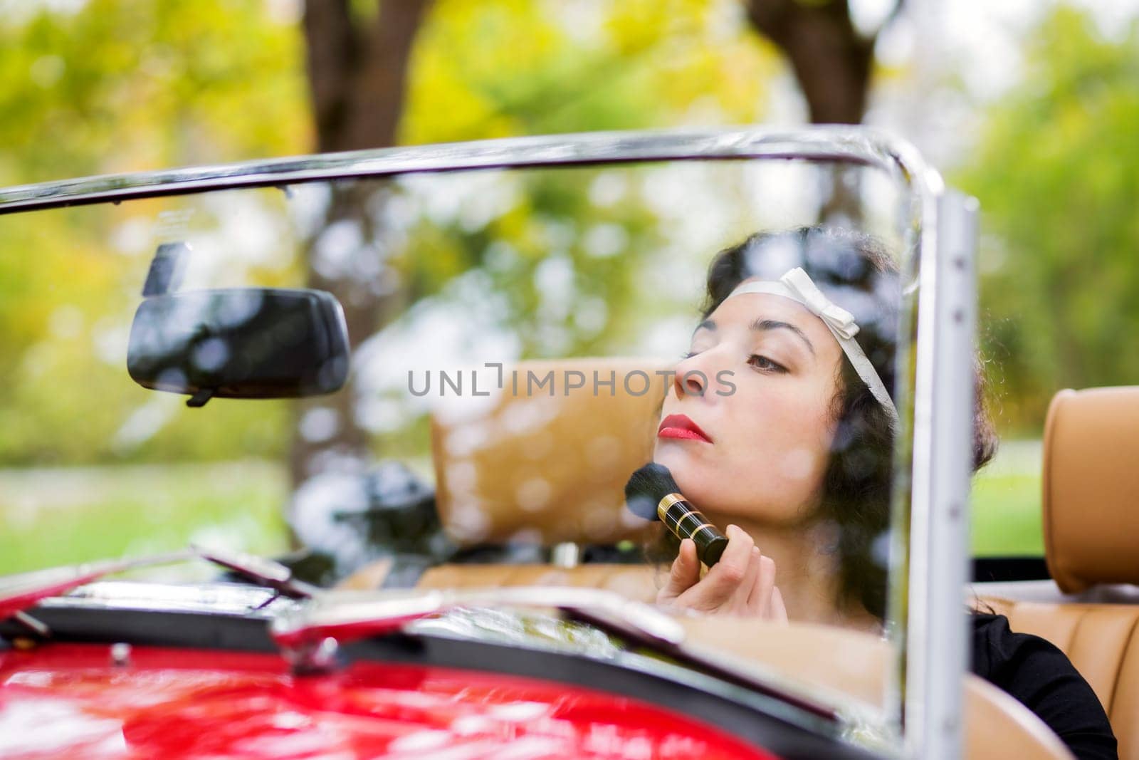 Woman adjust face before mirror at retro car