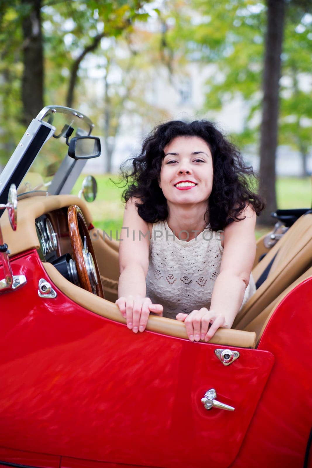 Happy woman in white dress at retro car