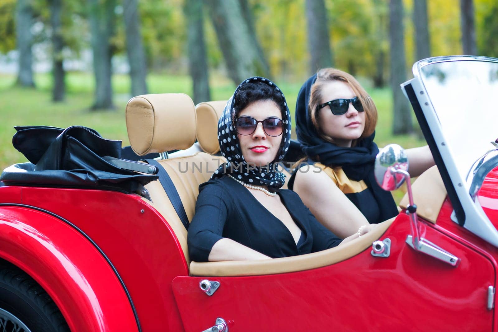 Fashionable women at retro car with dark glasses