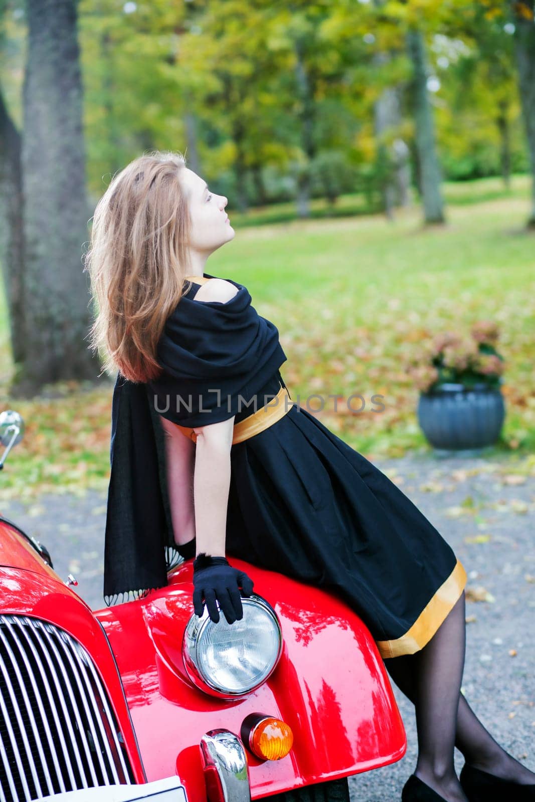 Woman in black posing on retro car headlight