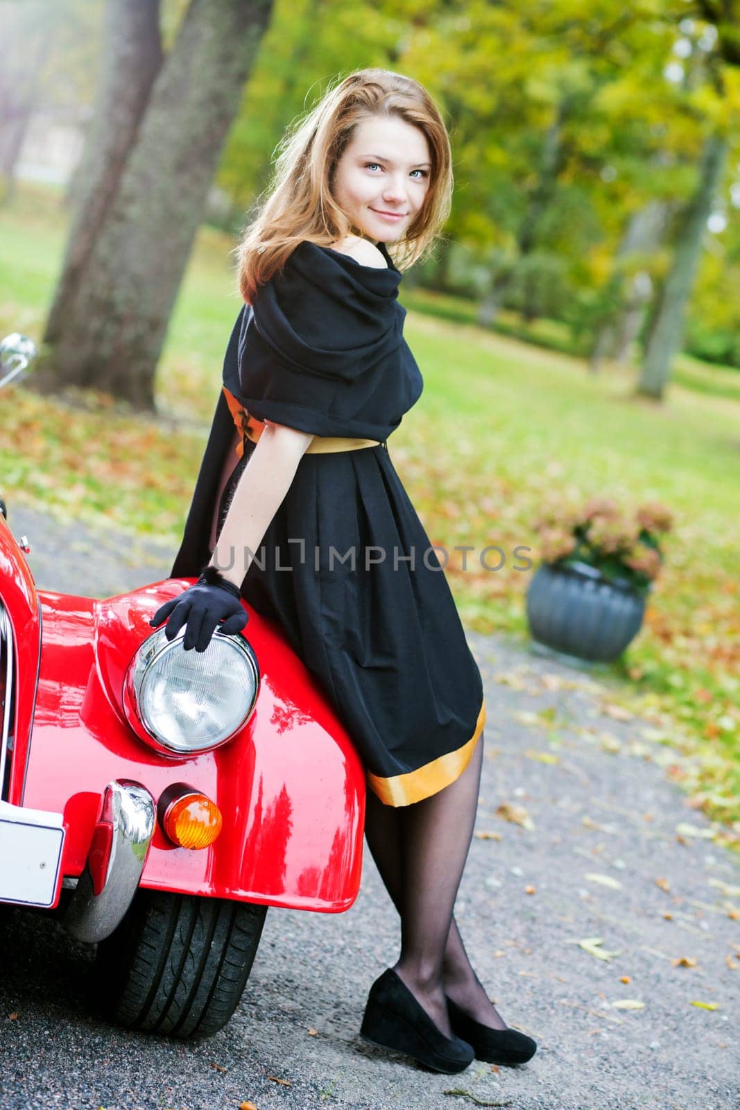 Happy woman in black and retro car headlight
