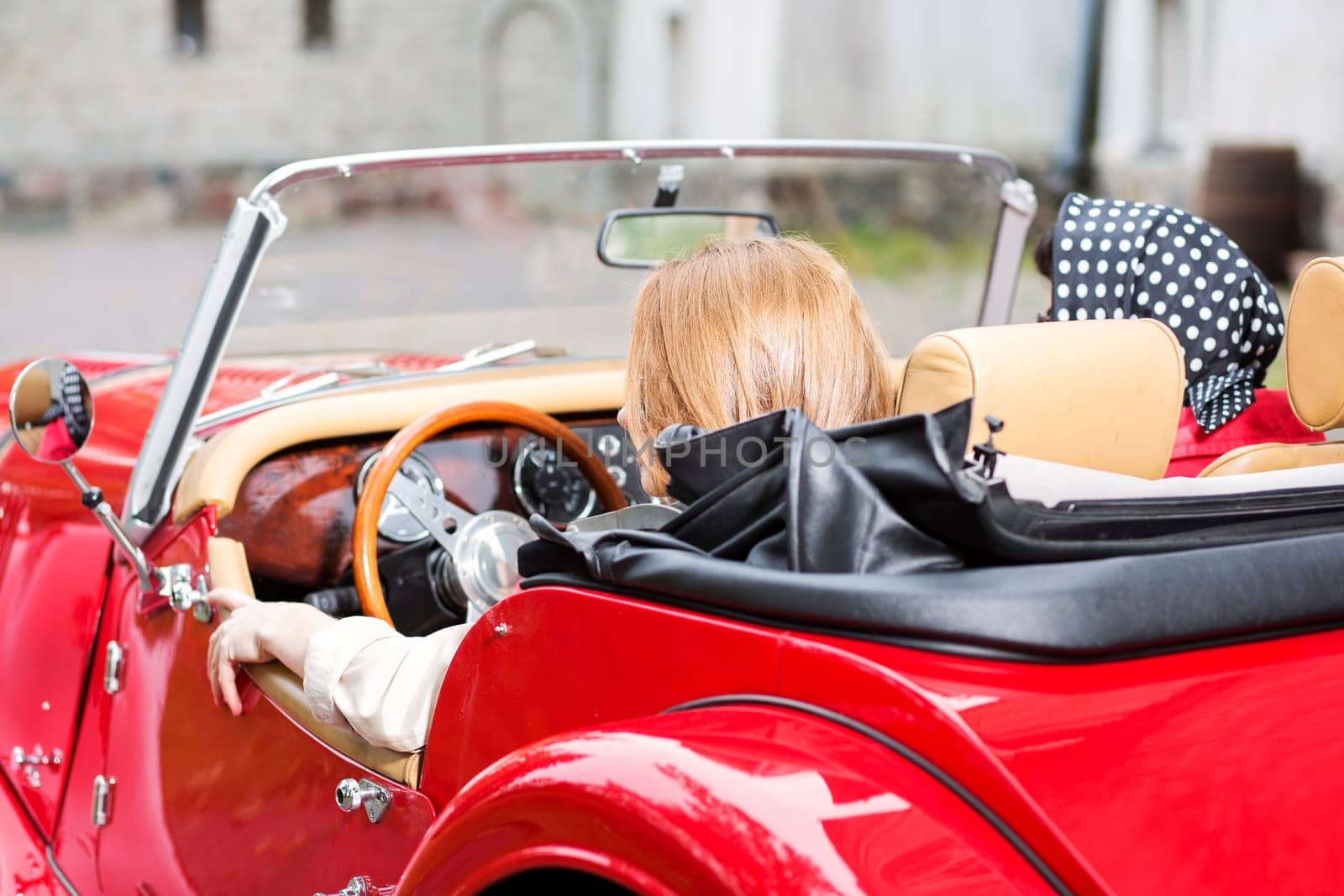 Pretty women at retro red car from behind