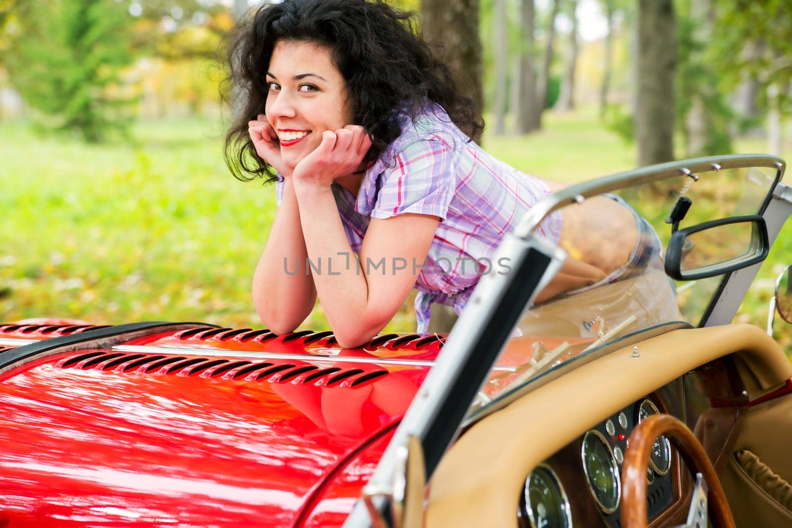 Smiling woman relay elbows on retro car cowling