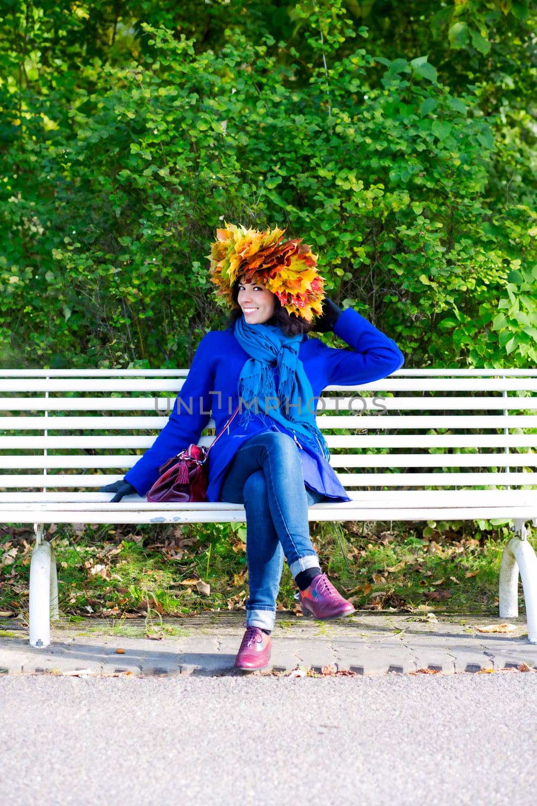 Happy young woman with maple leaves on head
