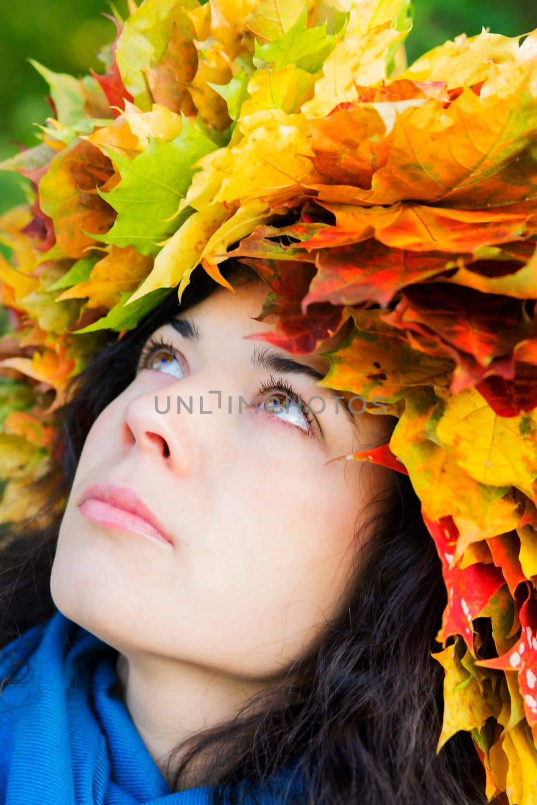 Woman with maple leaves on head look up