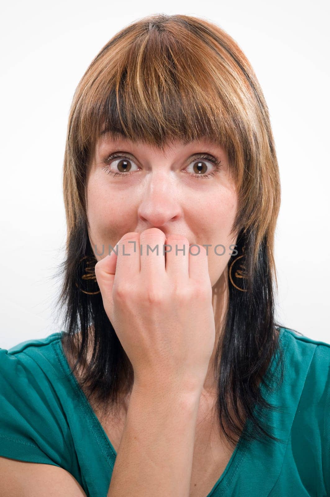 Head-and-shoulder shot of a young woman looking anxiously into the camera and holding her fingernails uncertainly to her mouth