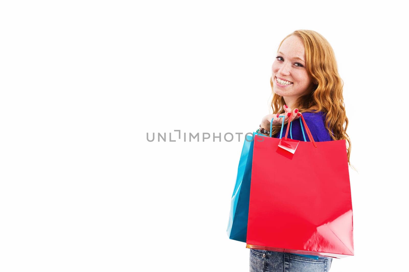 Happy young woman with shopping bags turns around against a white background