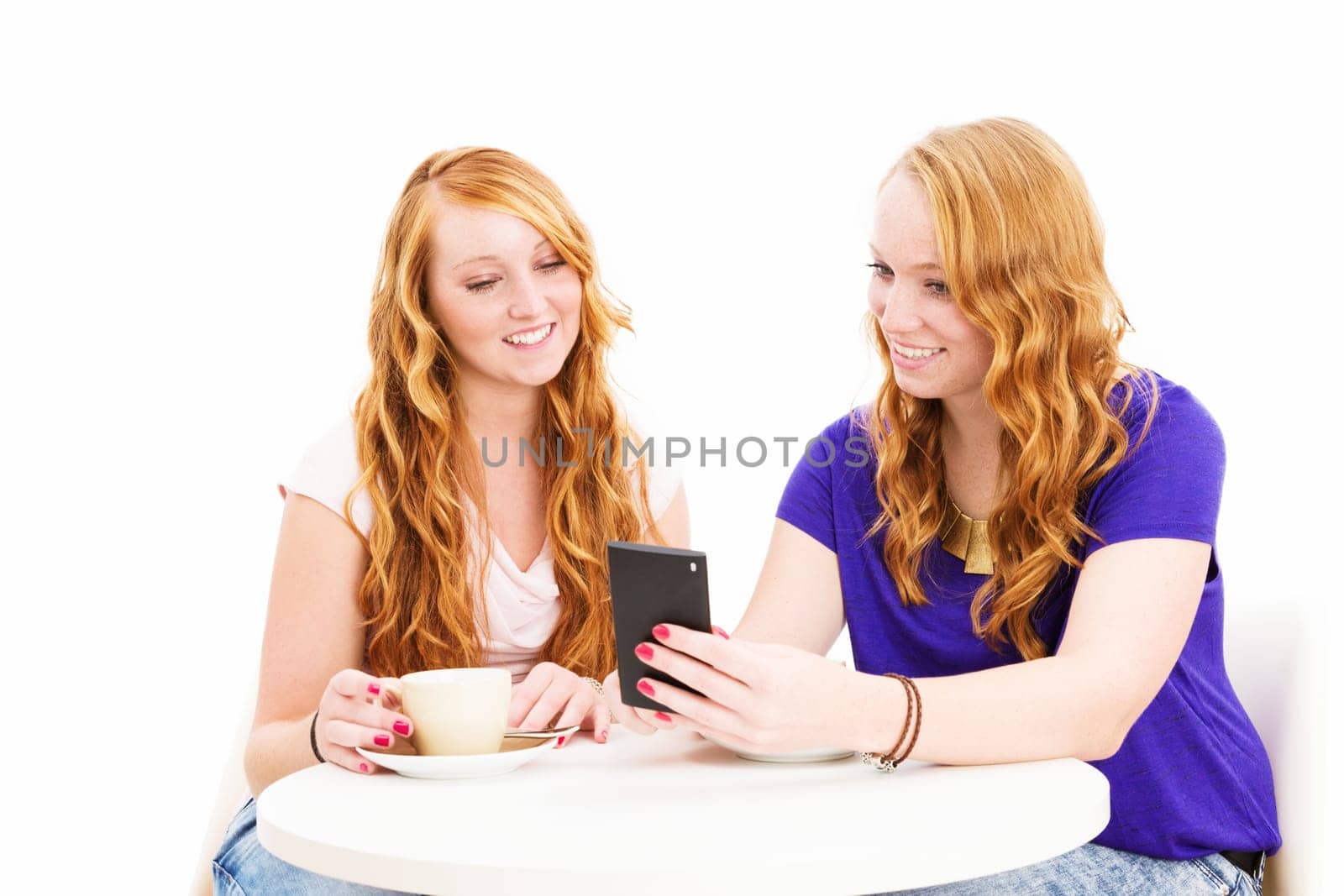 Two red-haired happy women look at their smartphone against a white background