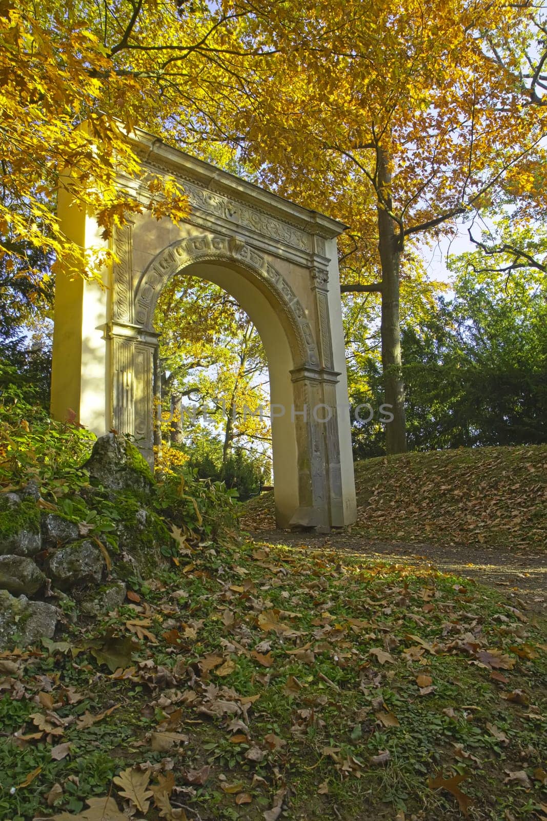 Autumn park with unknown romantic gate. Tree leaves are yellow.
