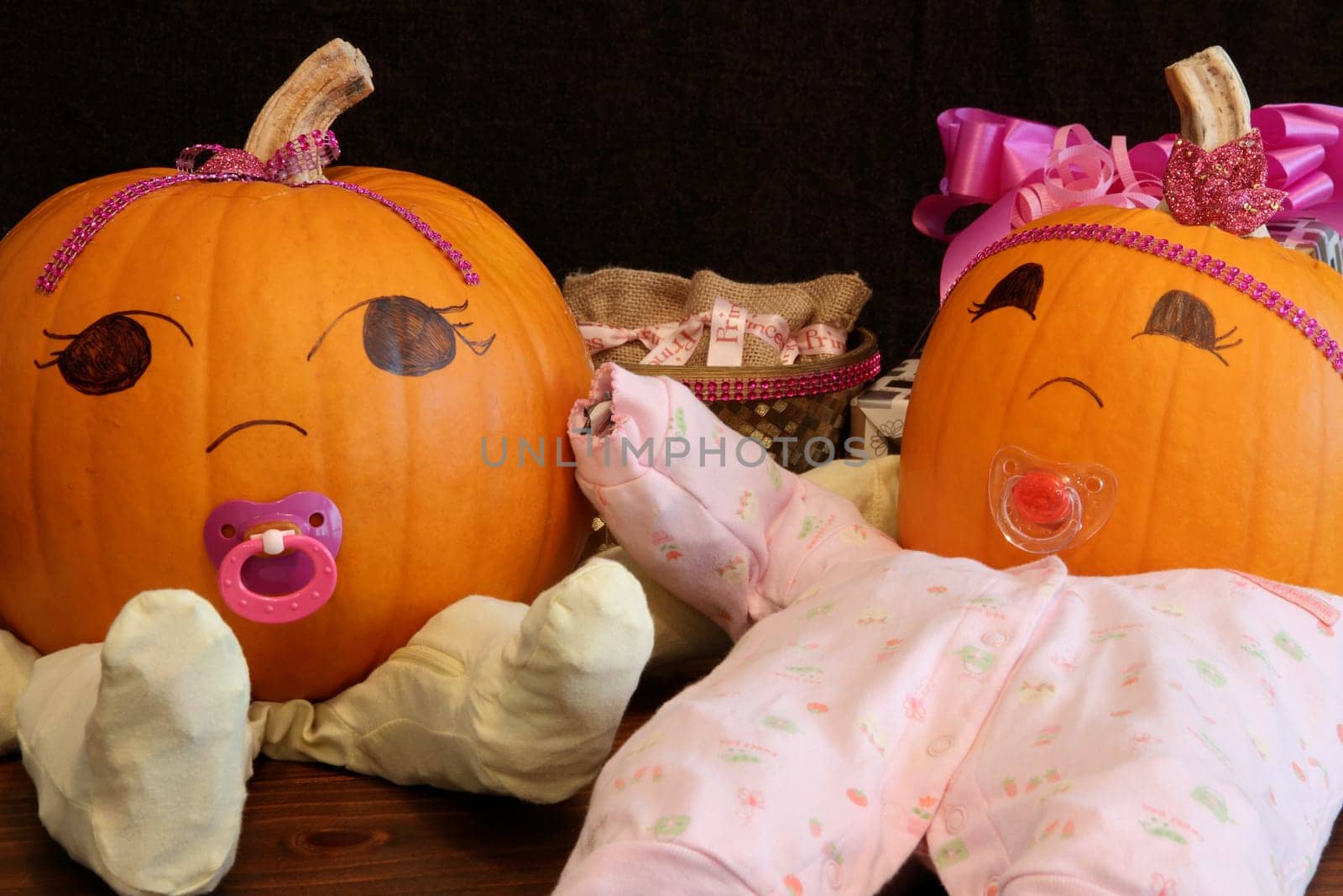 Two pumpkins dressed up as princess babies with pacifiers.