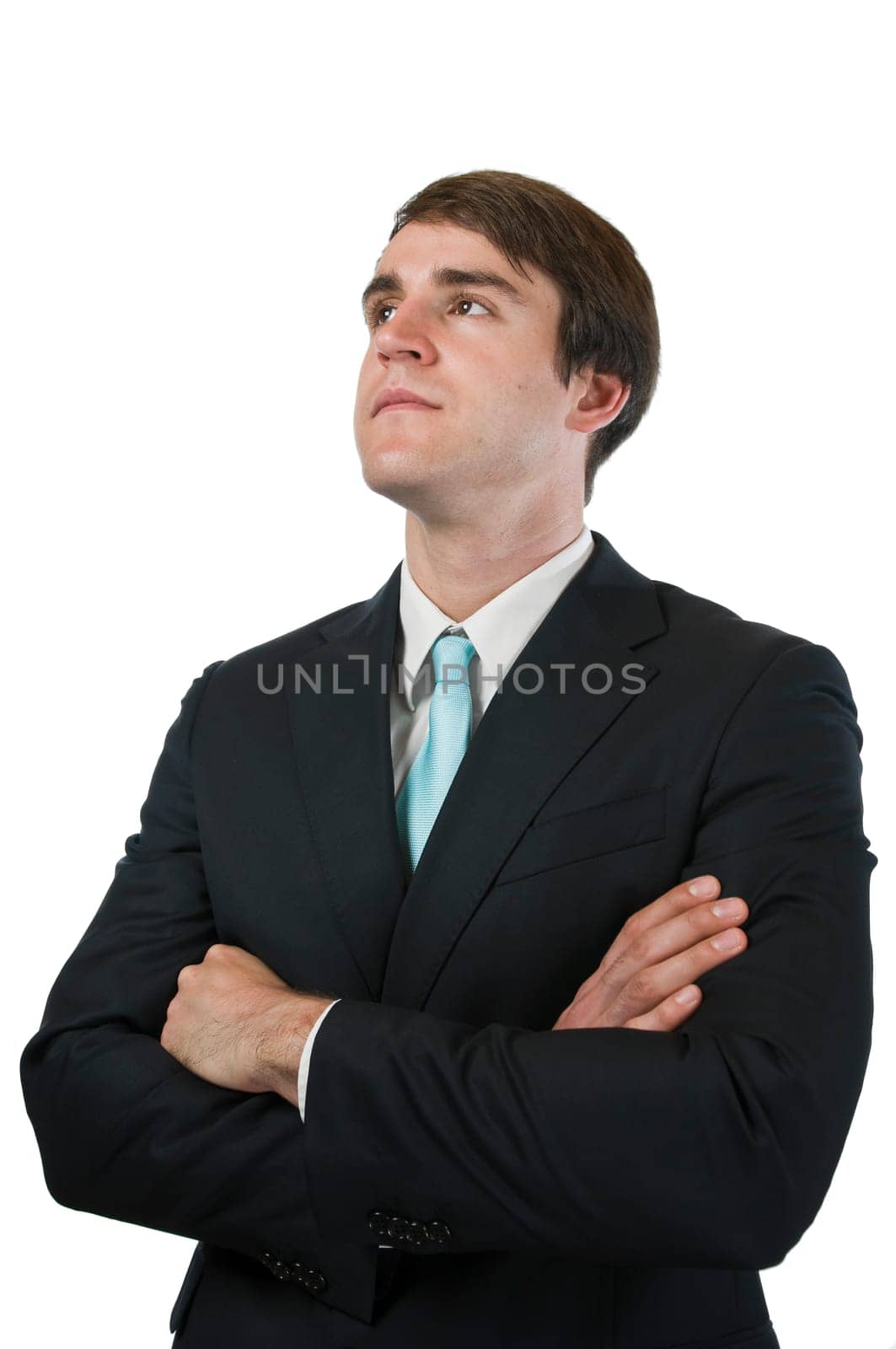 Upper body shot of a young man in a black suit and arms crossed against a white background looking diagonally upwards