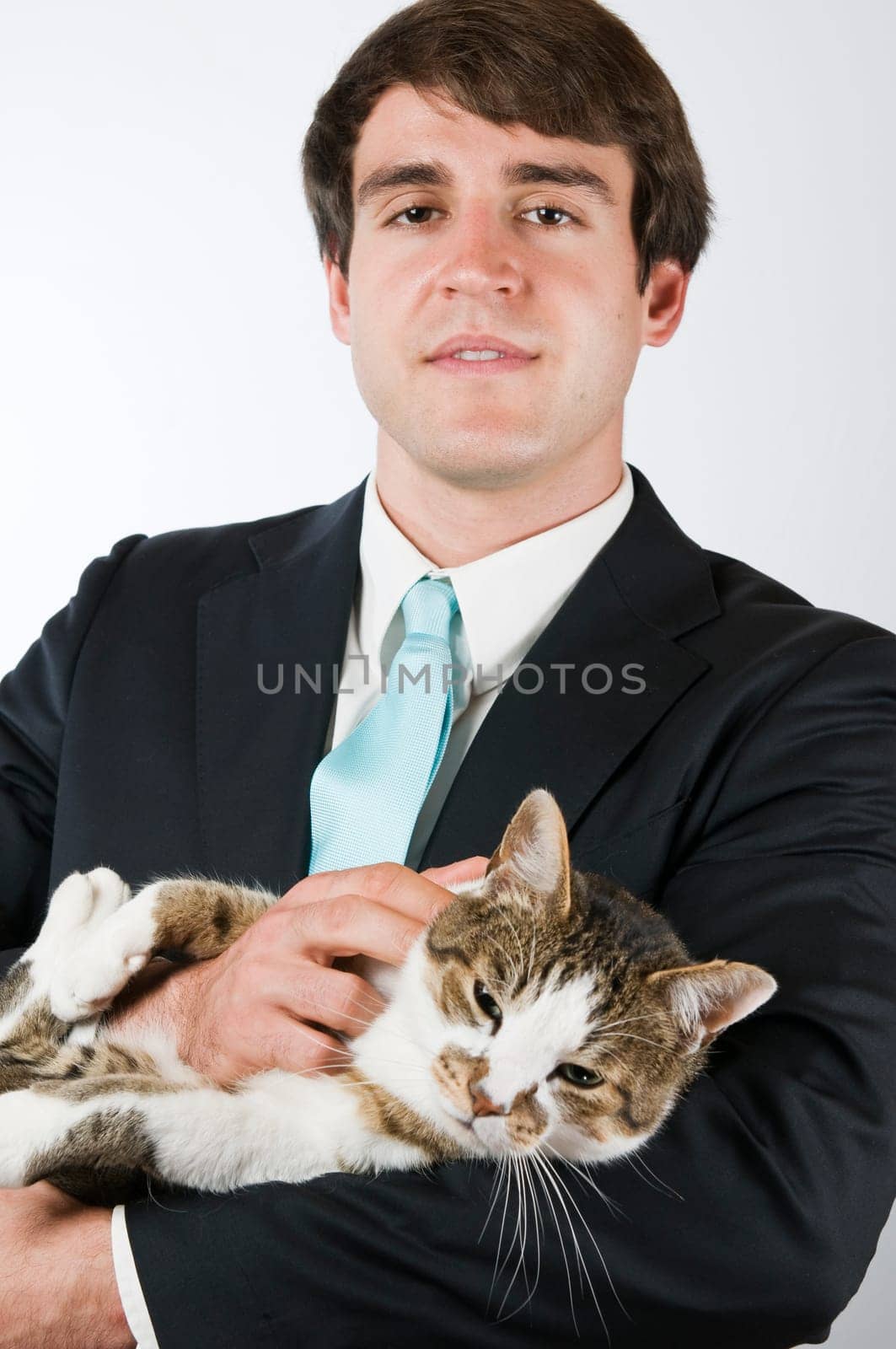 Upper body portrait of a man in a black suit with a wiggling cat in his arms smiling into the camera