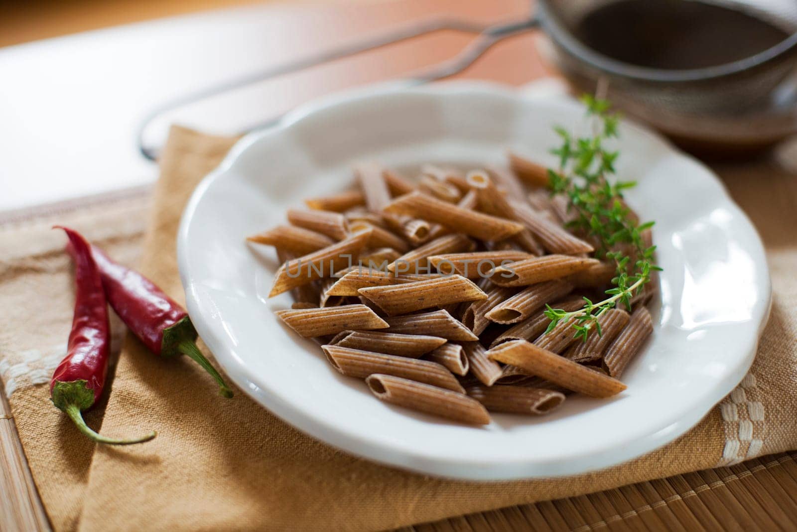 Raw whole pasta with chilli peppers on the table