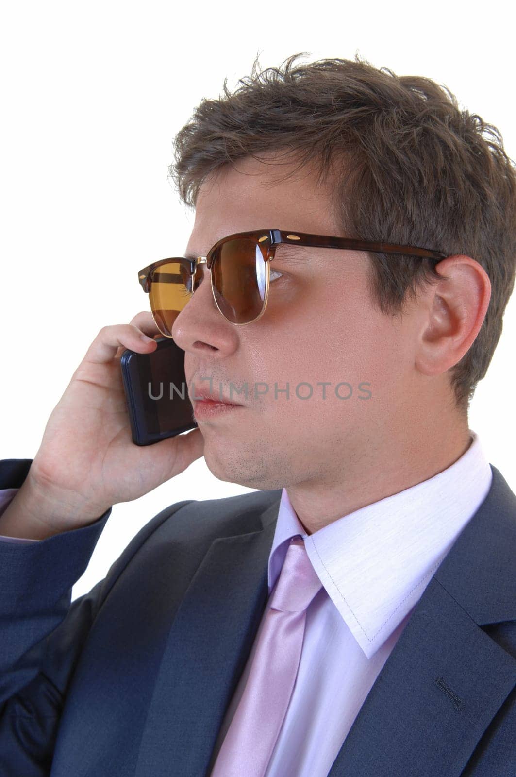 A young serious looking businessman on his cell phone in a blue suit.and tie and sunglasses, for white background..