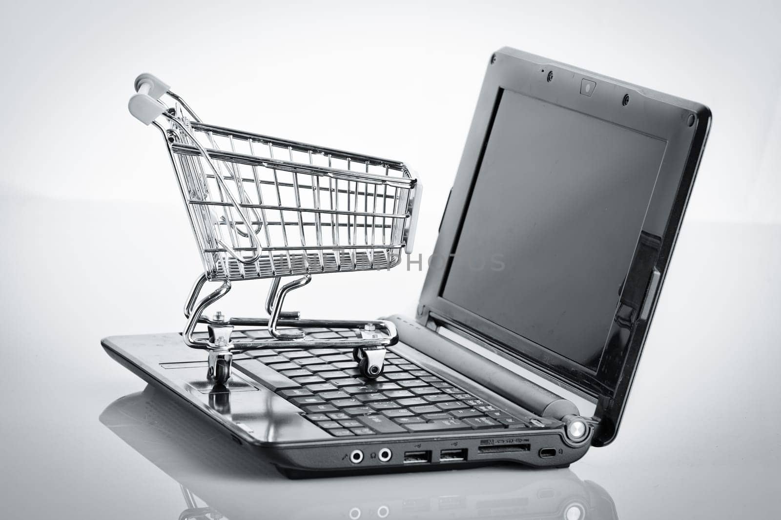 Online shopping. Shopping cart with notebook on the white. shopping cart over a laptop