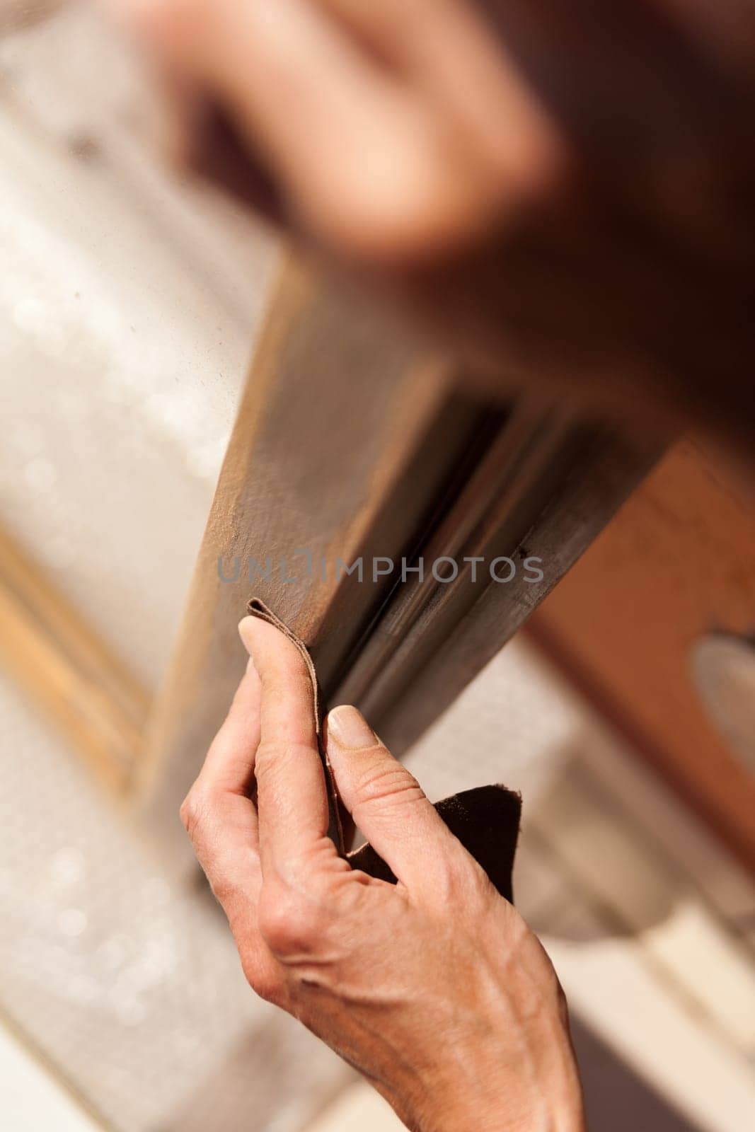 Hands of a woman with sandpaper doing DIY work on wooden fixtures