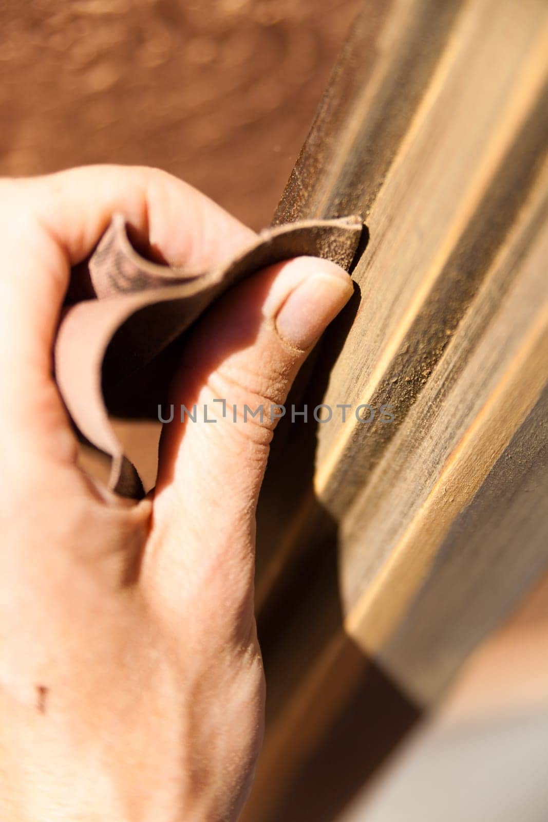Hands of a woman with sandpaper doing DIY work on wooden fixtures