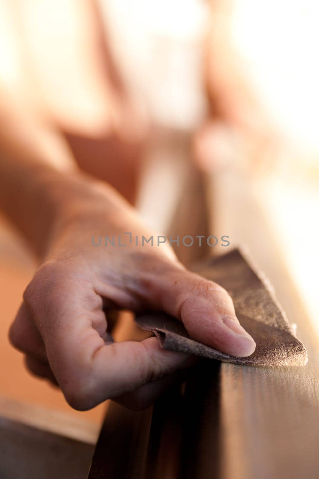 Hands of a woman with sandpaper doing DIY work on wooden fixtures