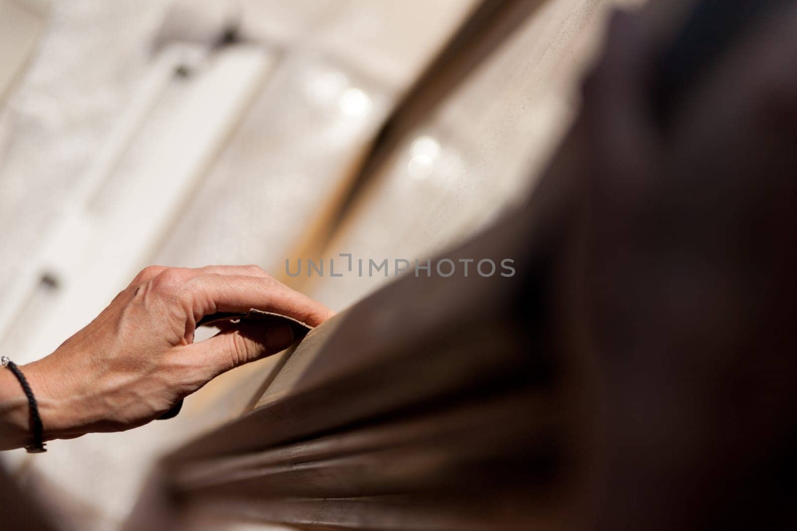 Hands of a woman with sandpaper doing DIY work on wooden fixtures