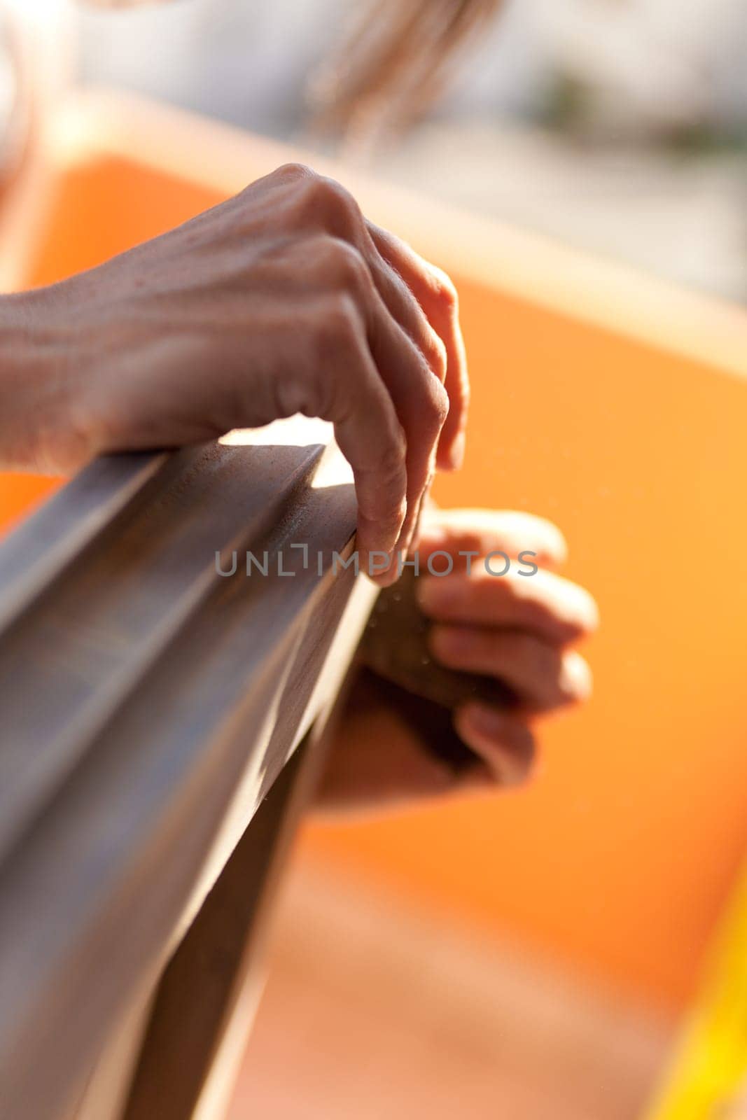 Hands of a woman with sandpaper doing DIY work on wooden fixtures