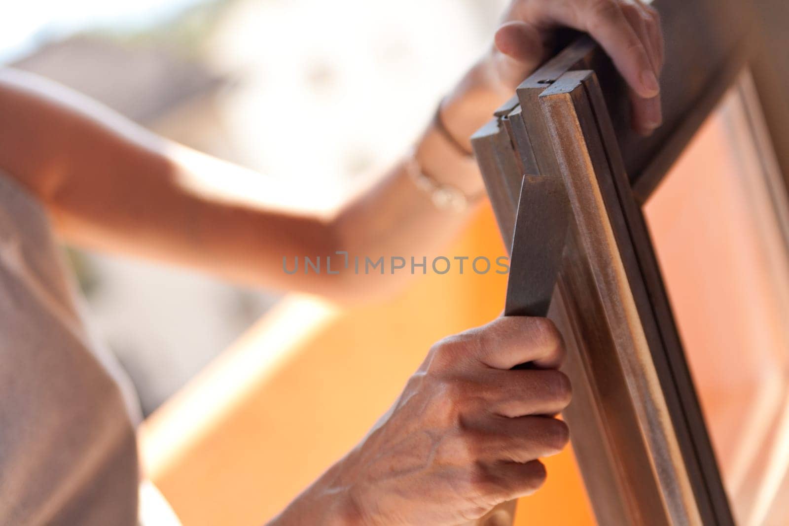Do it yourself scene with a girl removing paint from her window under the sun in her terrace