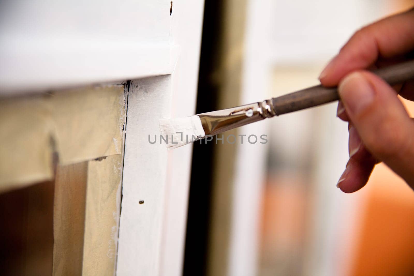 hands of a girl with a paintbrush painting a window as a do-it-yourself job