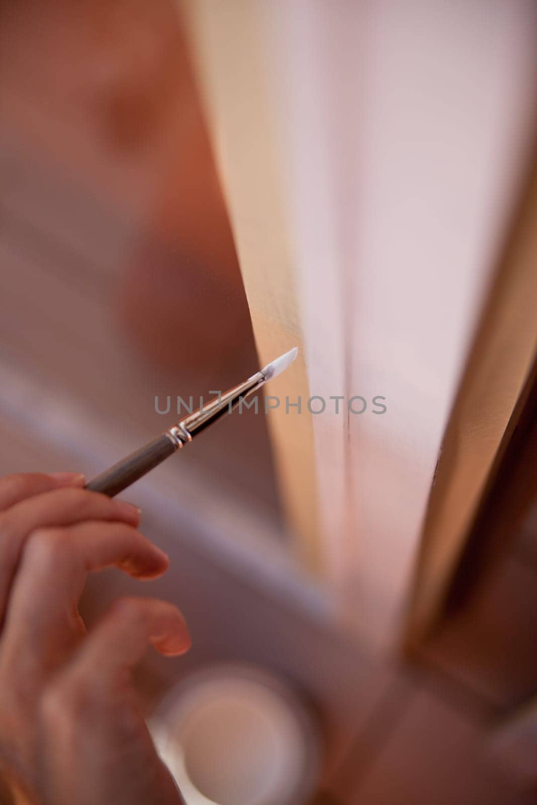 hands of a girl with a paintbrush painting a window as a do-it-yourself job