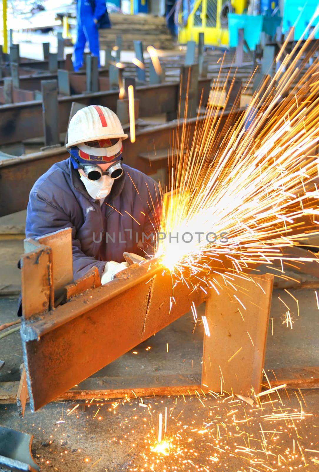 worker using torch cutter to cut through metal in factory