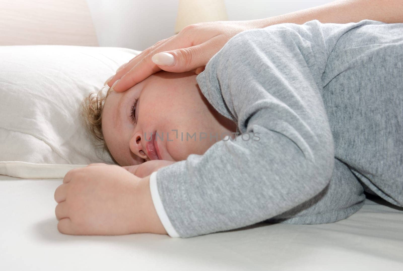 little blond boy, relaxed sleeping on her bed wrapped in a soft blanket