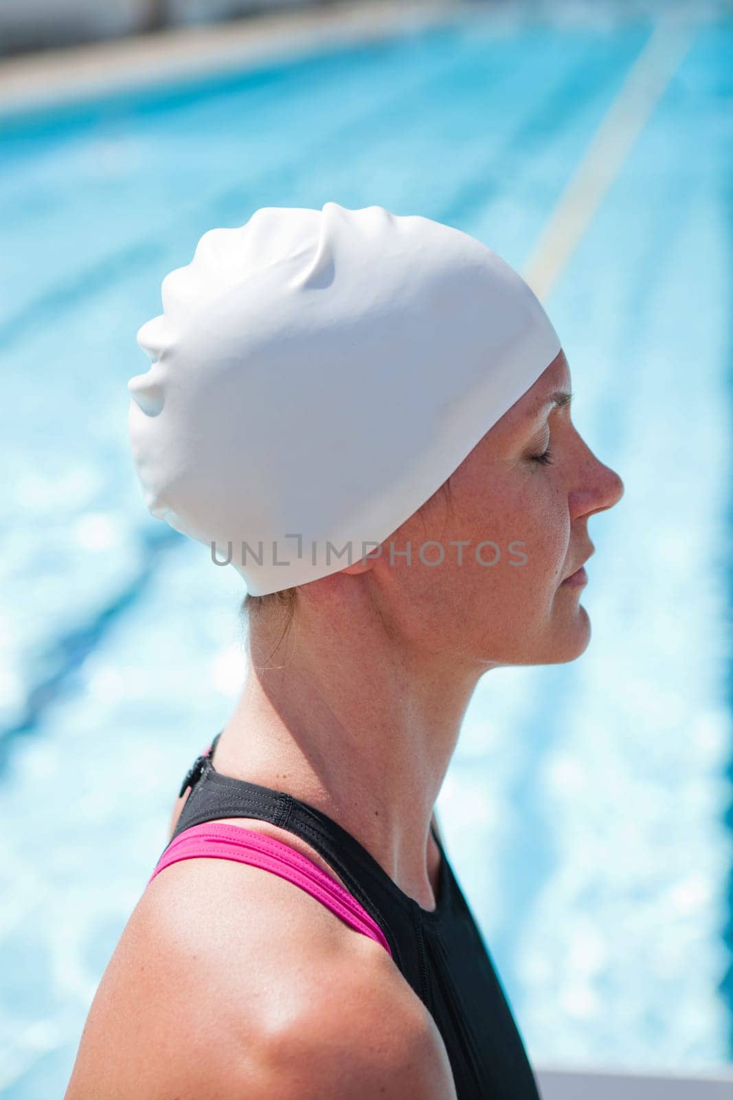 Female swimmer beside swimming pool concentrating with eyes closed