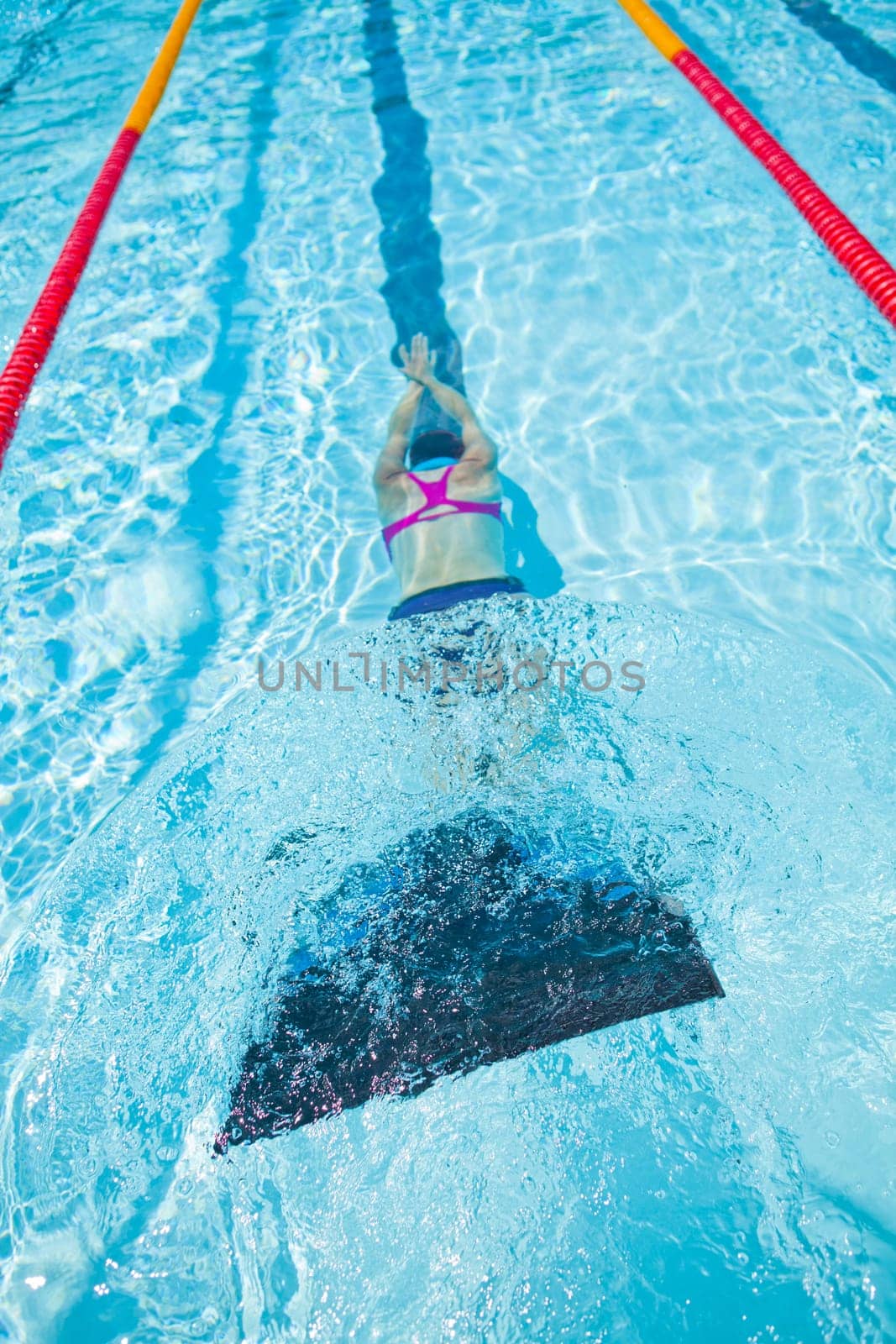 Female freediver with monofin swimming underwater in swimming pool