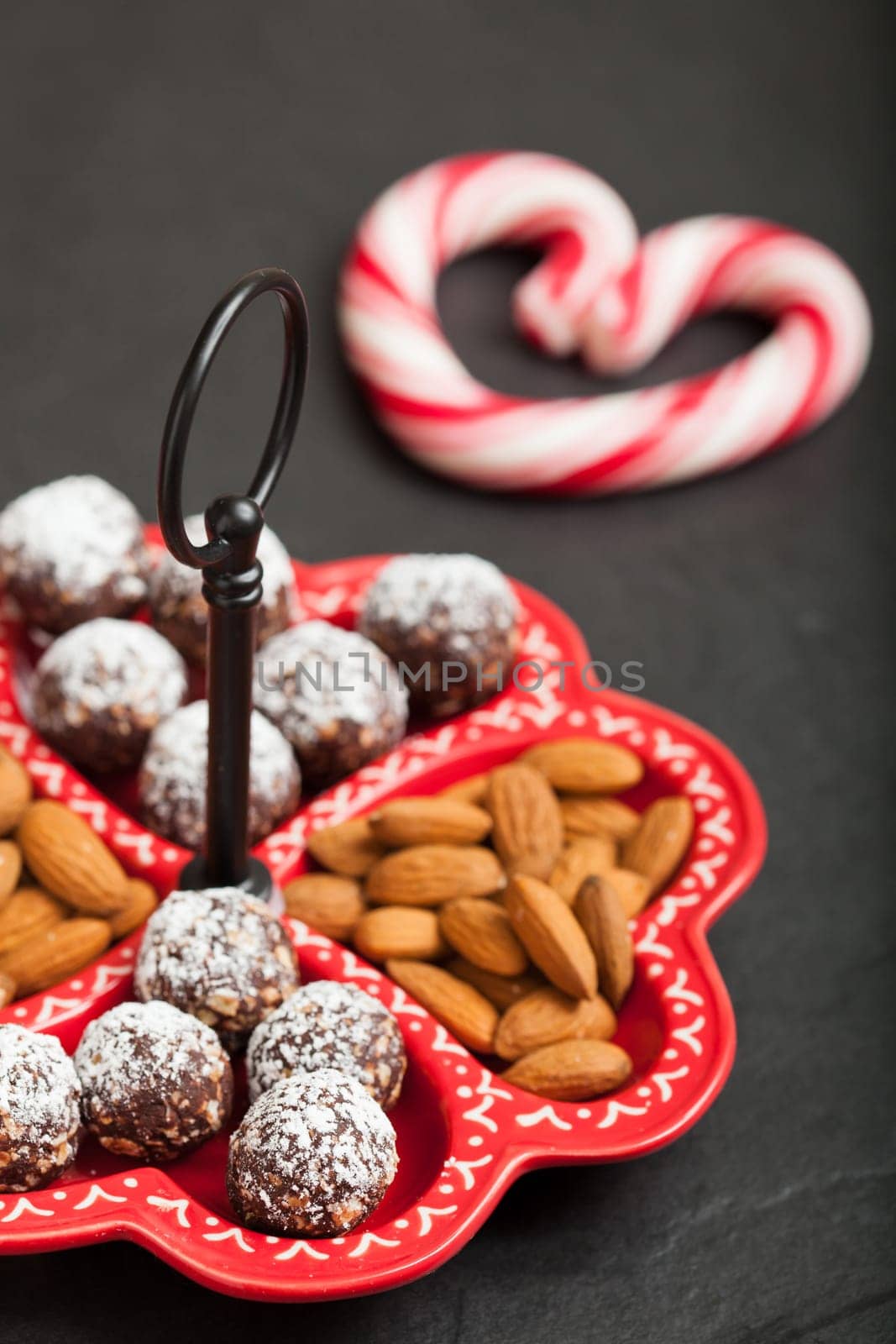 Closeup of tray of almonds and chocolate balls with hard handy heart with red swirls in background