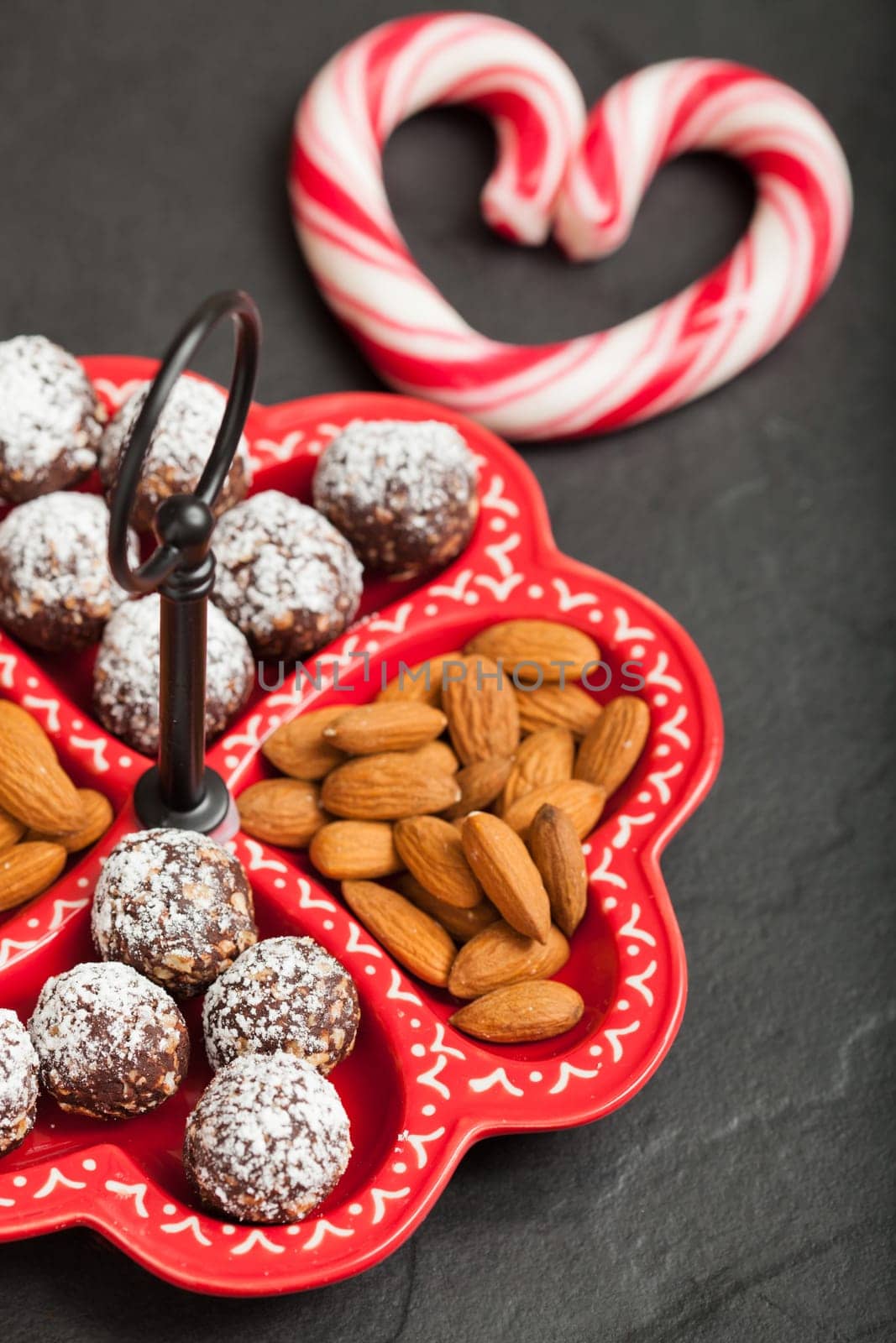 Closeup of tray of almonds and chocolate balls and hard handy heart with red swirls