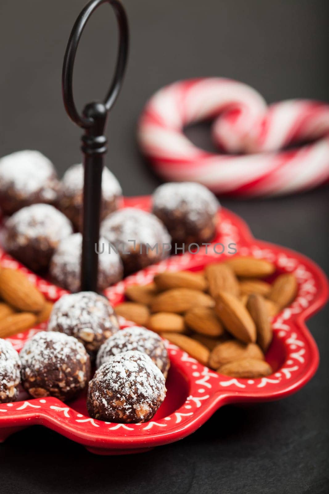 Closeup of tray of almonds and chocolate balls with hard handy heart with red swirls in background