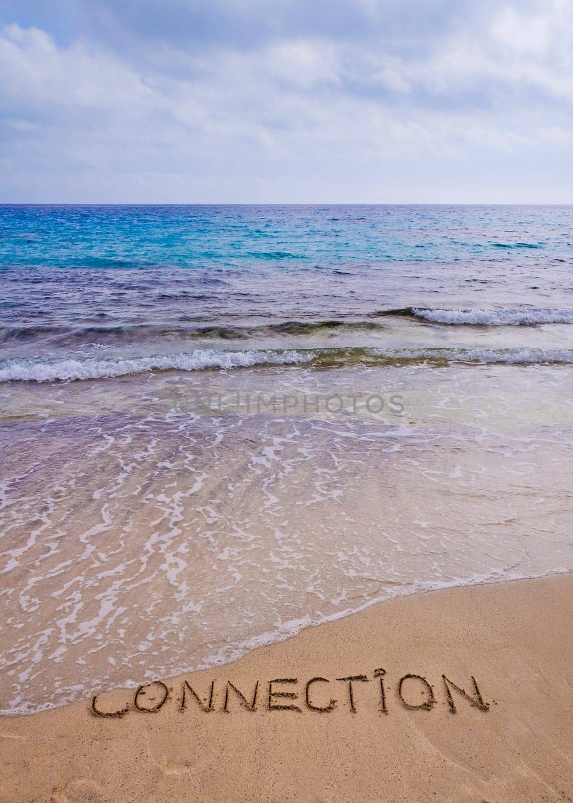 Connection word written on sand, with waves in background, connecting concept
