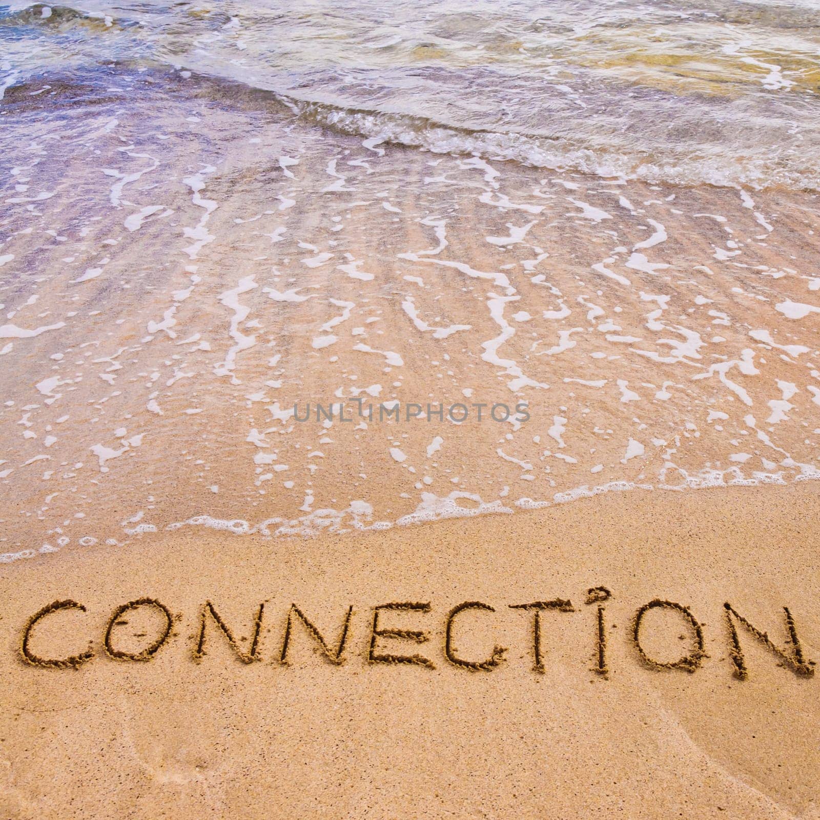 Connection word written on sand, with waves in background, connecting concept