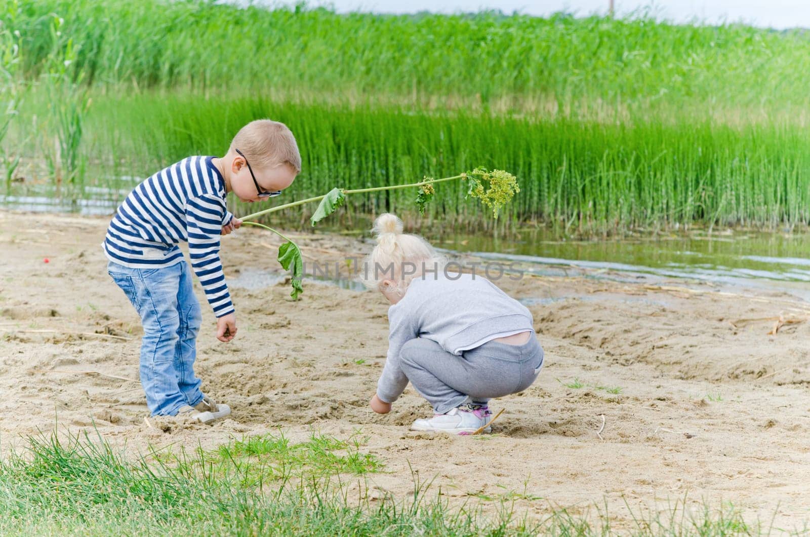 Boy and girl playing in the sand on the shore of Lake