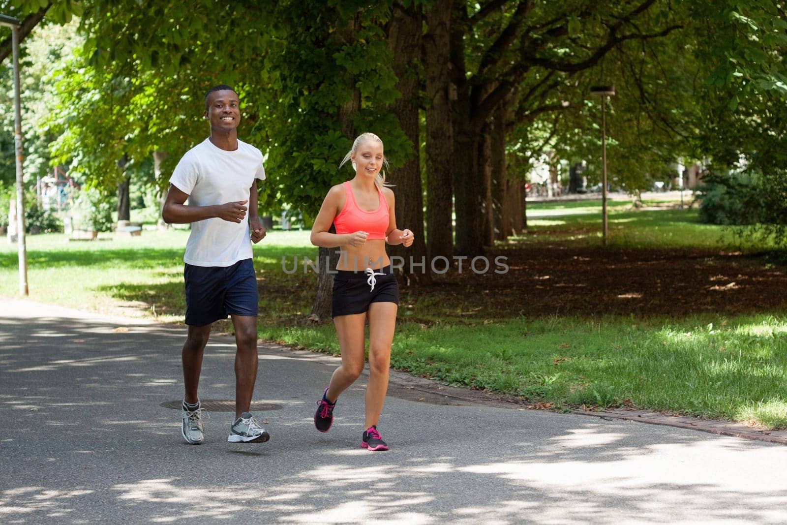 Two sporty young joggers running in the park in summer training health
