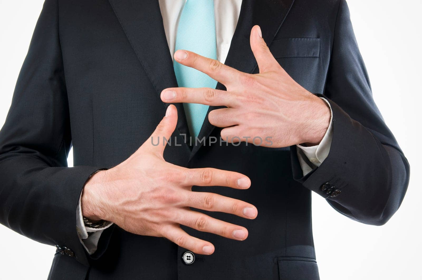 Chest-and-stomach view of a young man in a black suit with his hands held in front of him indicating the "8"" (eight fingers)"