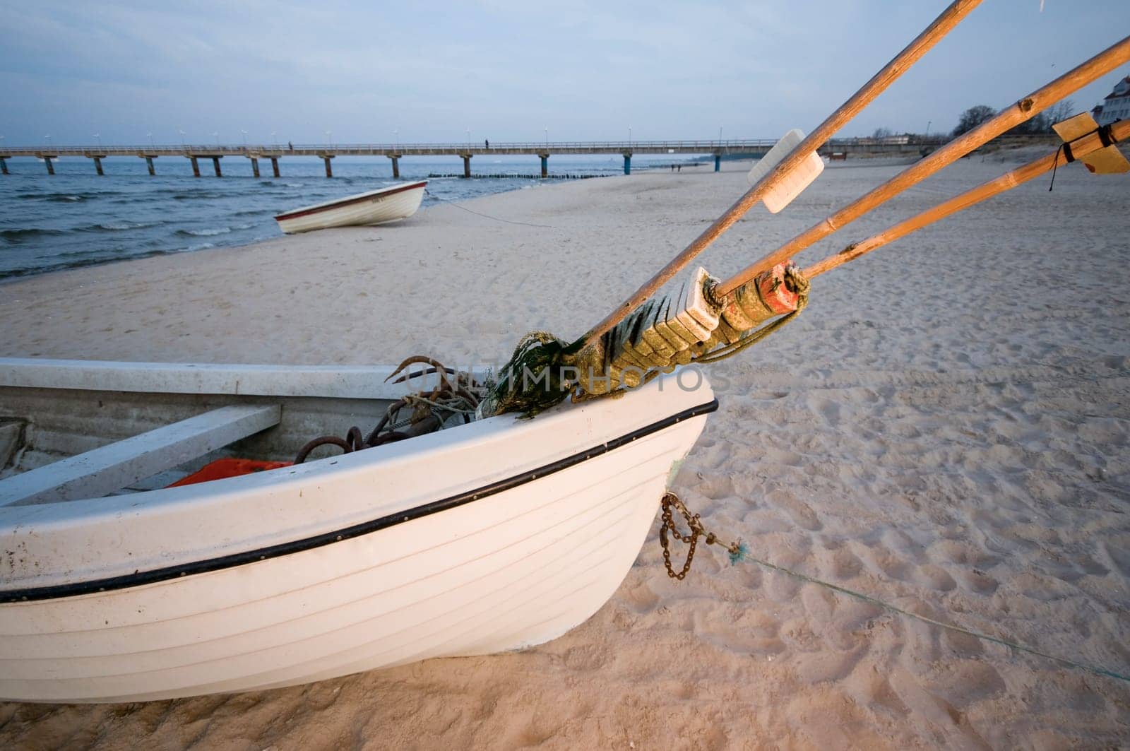 Detail view of a small fishing boat on the Baltic Sea Beach at sunset on the island of Usedom in the summer  Pier in the blurry background.