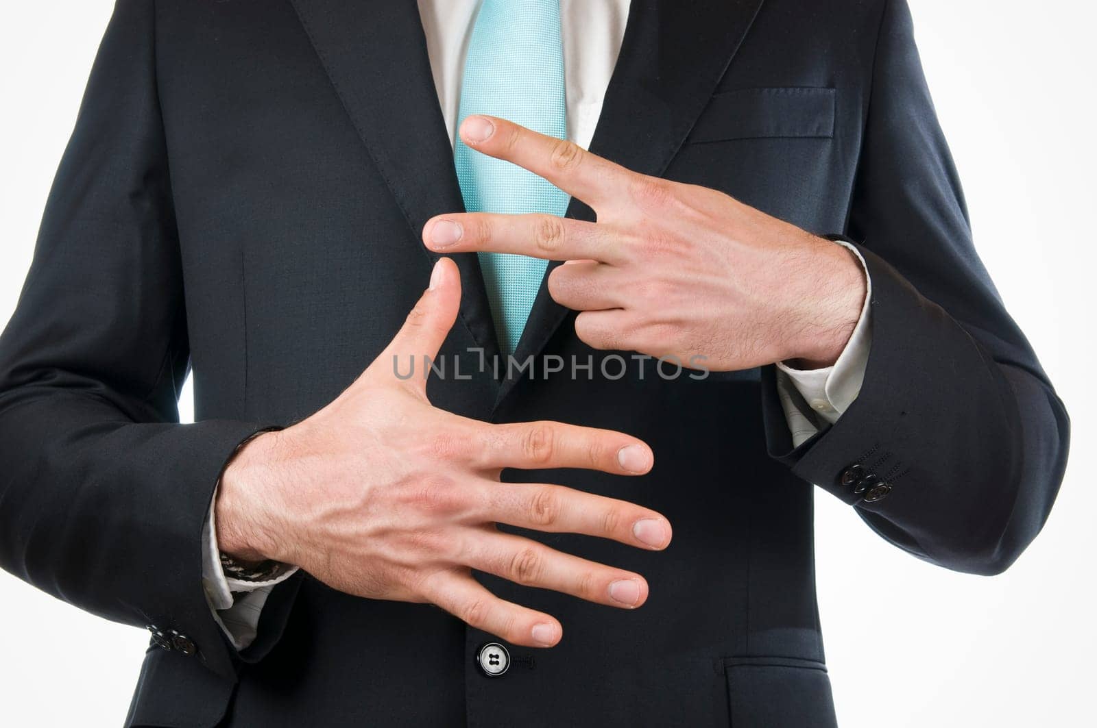 Chest-and-stomach view of a young man in a black suit with his hands held in front of him indicating the "7"" (seven fingers)"