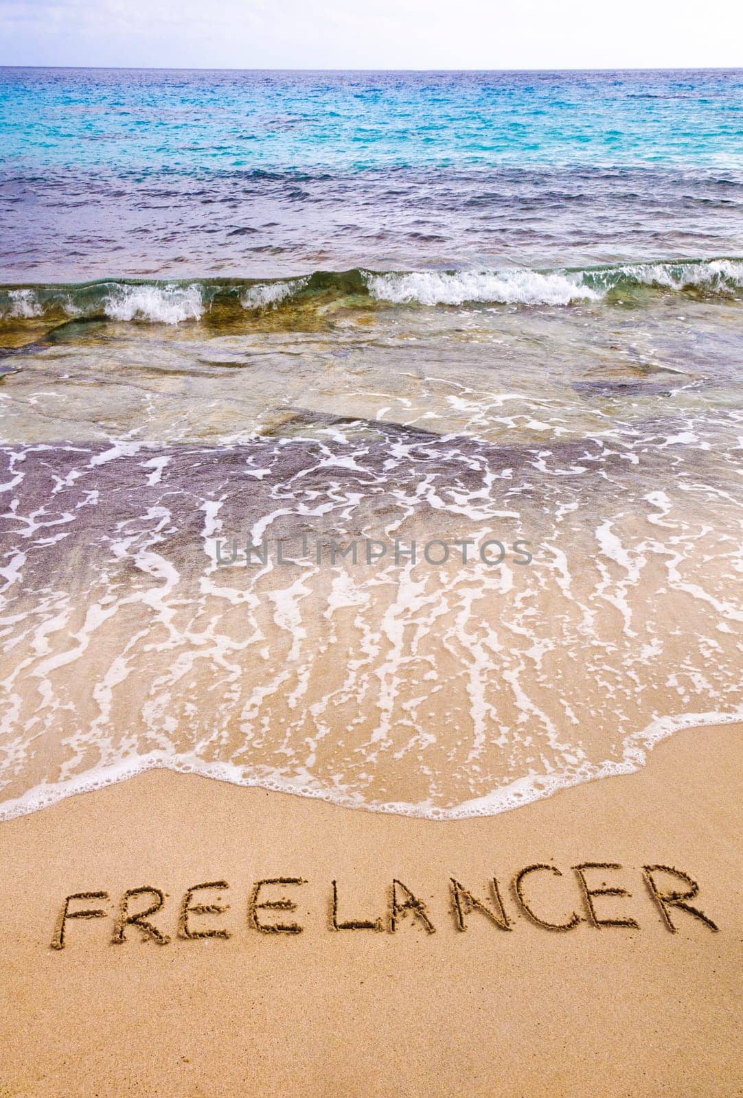 Word FREELANCER written in sand, on a beautiful beach, Freelance concept