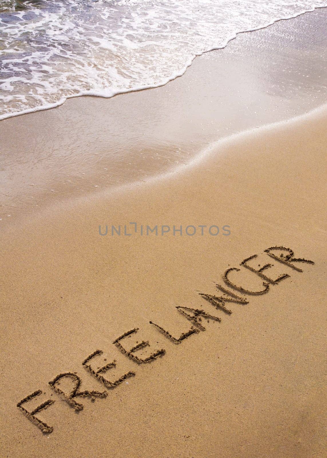 Word FREELANCER written in sand, on a beautiful beach, Freelance concept
