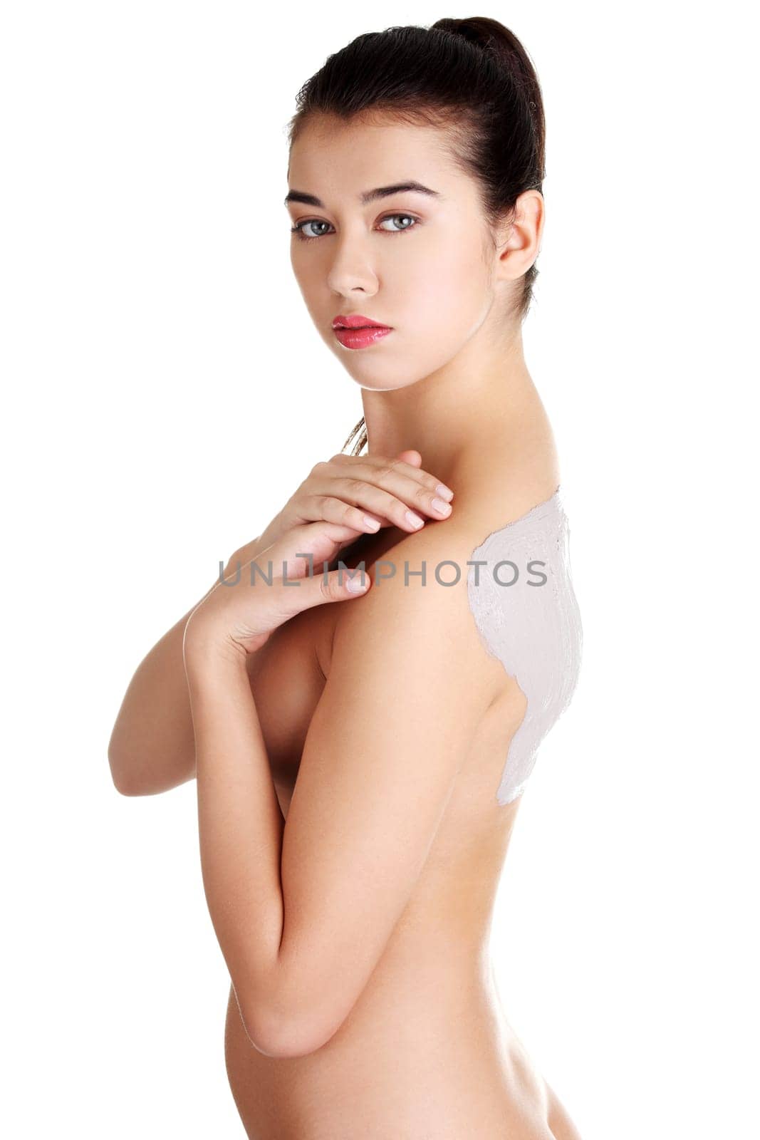 Charming nude woman enjoying a mud skin treatment on her back. Isolated on white