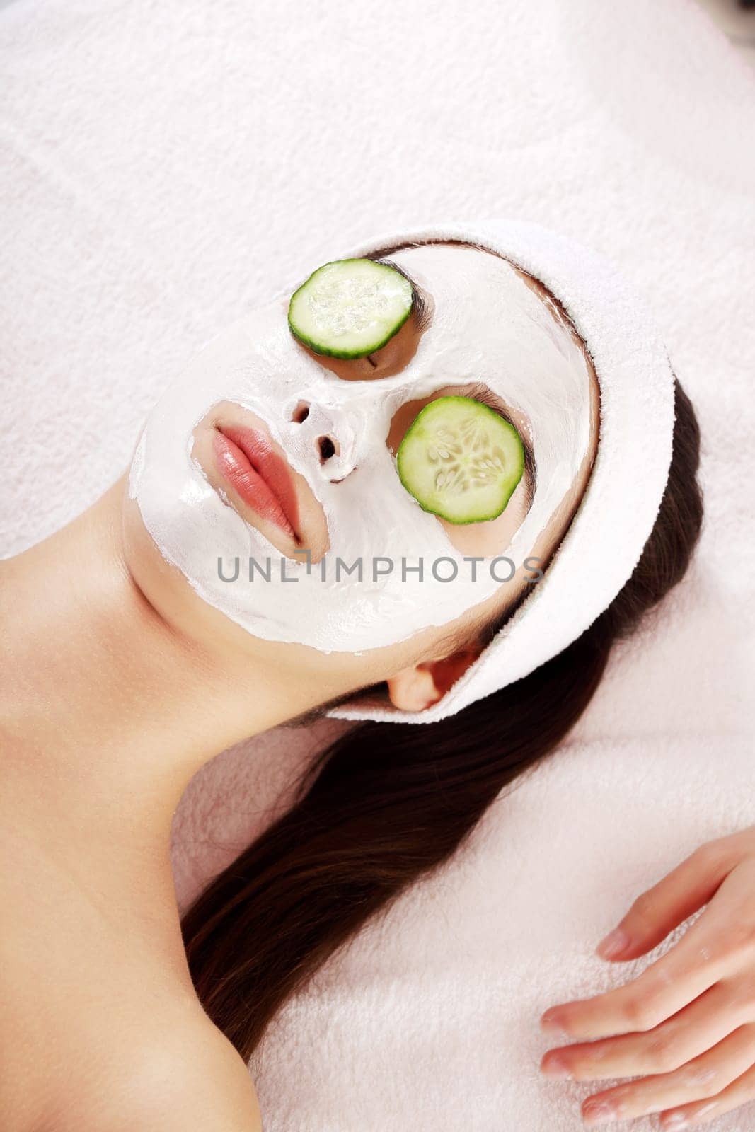Young woman with cucumber slices on the face in a spa saloon