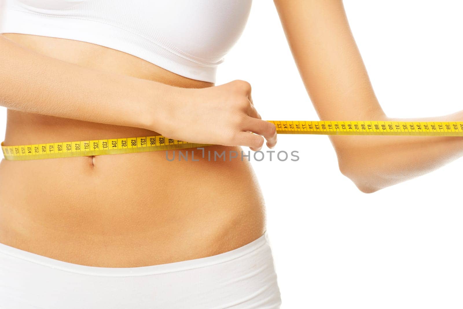Slim fit woman in white panties with measure tape on white background